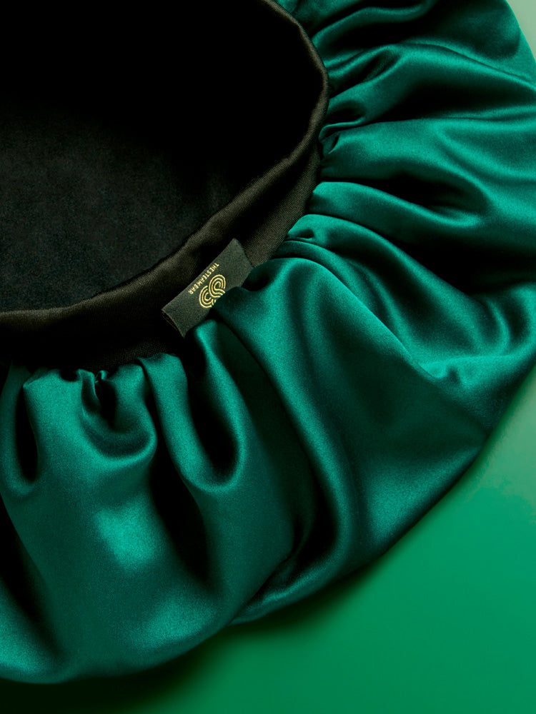 The Steam Bar's Satin Bonnet product up close showcasing the jade green satin material and elasticated band