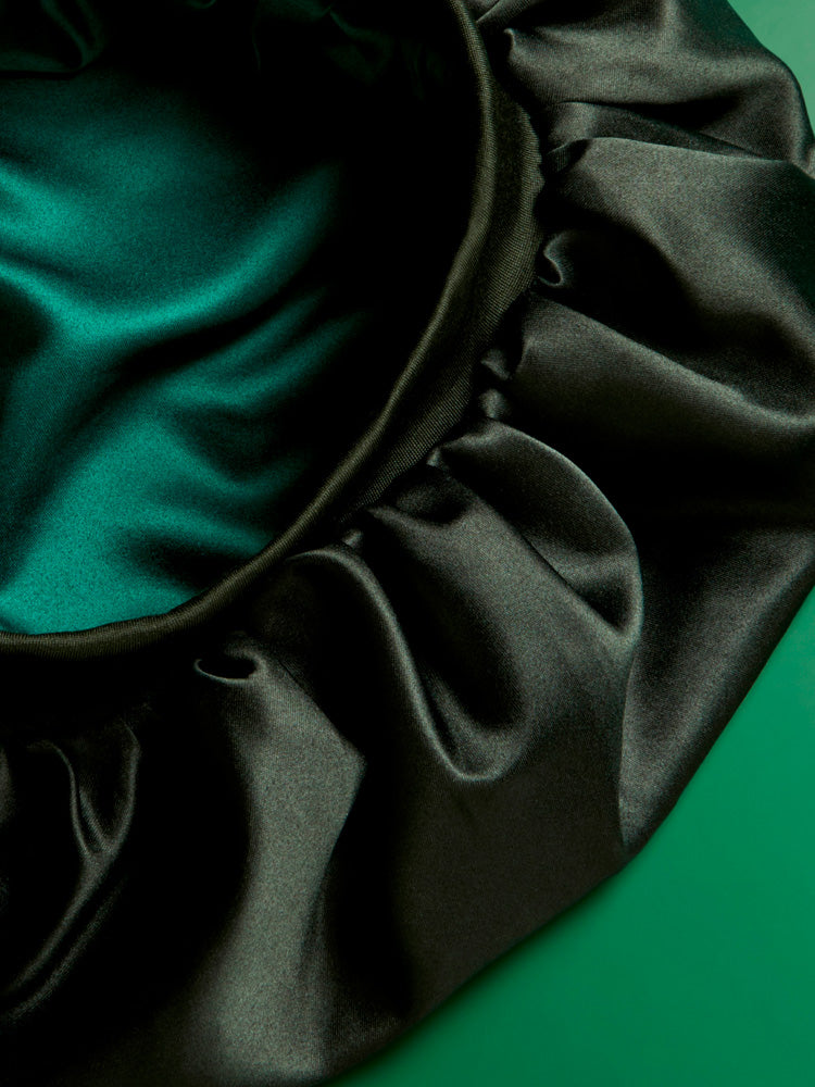 The Steam Bar's Satin Bonnet product up close, showcasing the reversible black satin material and elasticated band