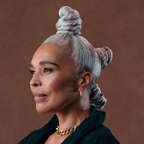 Older black female model with grey hair styled and posing elegantly and proudly into camera